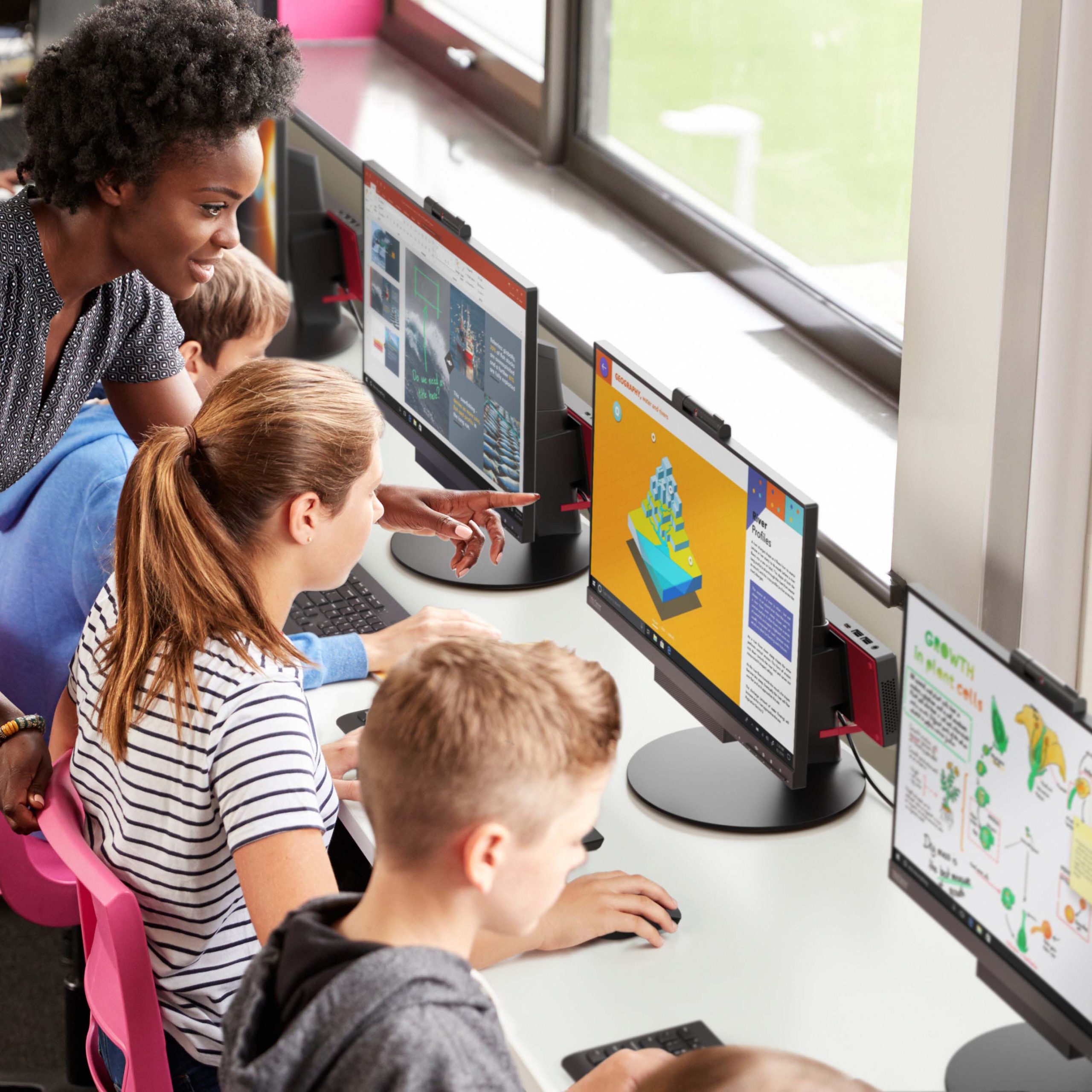 Lifestyle Foto Lenovo Campus ThinkCentre M90N Education Lehrer hilft weiblichen Schülern, die im Computerunterricht an Bildschirmen arbeiten. Zu sehen sind fünf ThinkCentre M90N.