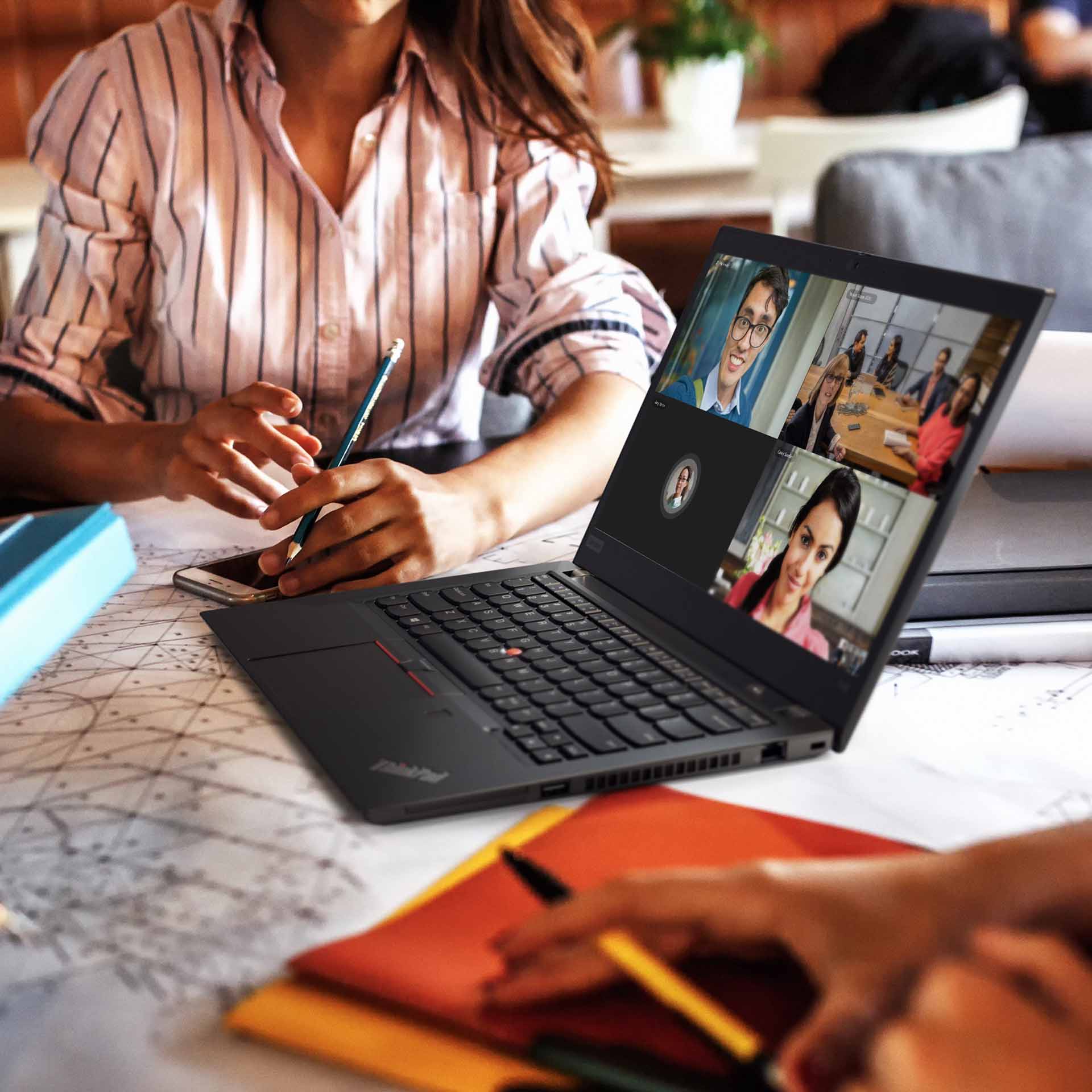 Lifestyle Foto Lenovo Campus ThinkPad Universität Studenten sitzen in der Universität und sind eifrig am Lernen. Während eines Videoanrufs auf einem Lenovo ThinkPad zeichnen sie Notizen, konzentriert auf das, was sie hören und sehen. Die Szene vermittelt eine Mischung aus Technologie und traditionellem Lernen.
