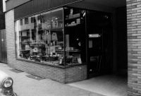 Das Bild zeigt das Schaufenster in der Gagernstraße in Darmstadt aus dem Jahr 1967, fotografiert von rechts. Das Foto in Schwarz-Weiß vermittelt einen historischen Eindruck des Geschäfts und seiner Auslage, wodurch die Atmosphäre der damaligen Zeit eingefangen wird.