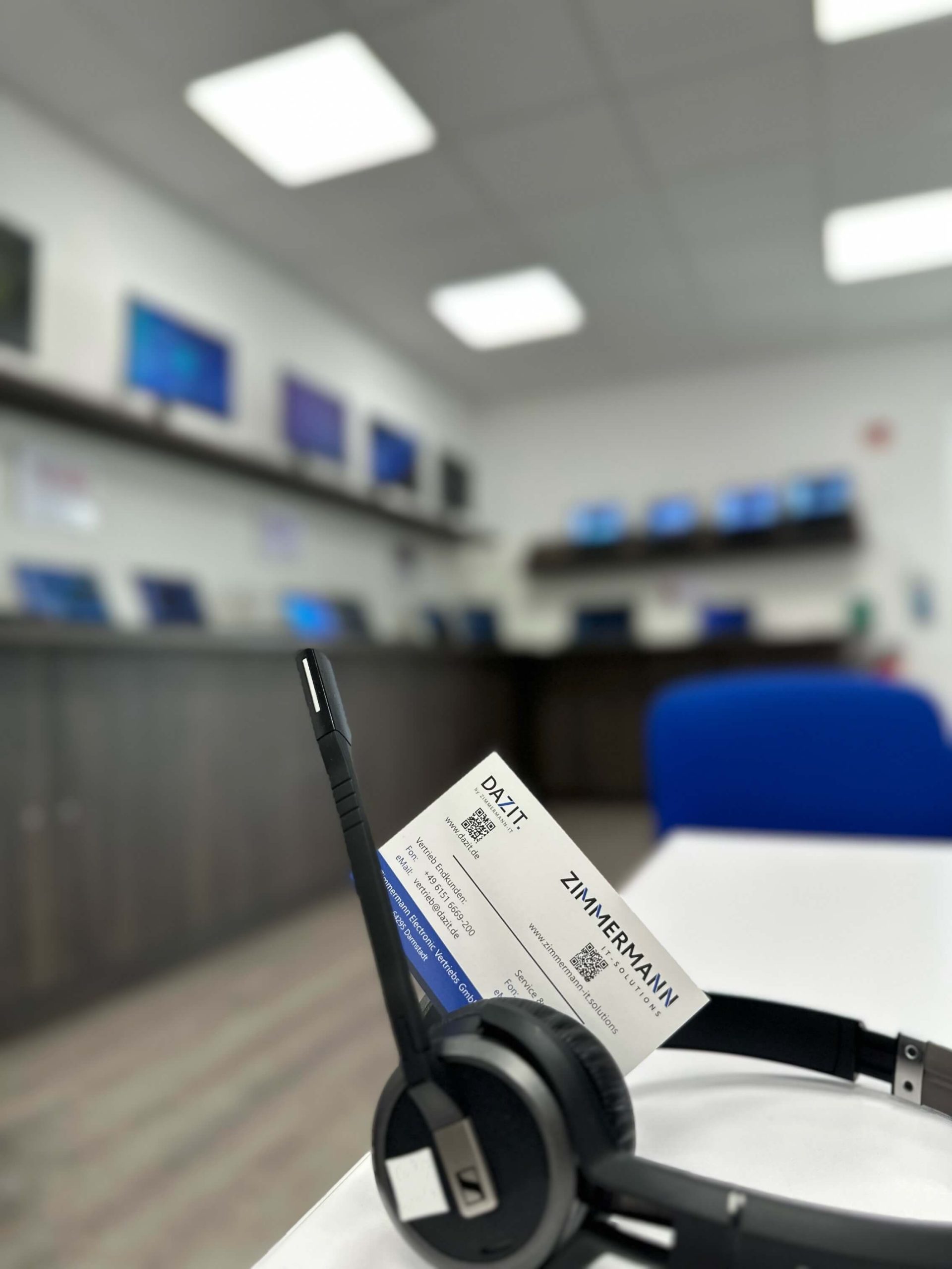 Das Bild zeigt ein Headset im Showroom, daneben liegt eine Visitenkarte. Die Szene vermittelt einen professionellen Eindruck und hebt die Präsentation von Kommunikationszubehör im Ausstellungsraum hervor.